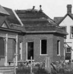 this house being built ca 1909, workers on the roof in this photo, curved porch not added yet.